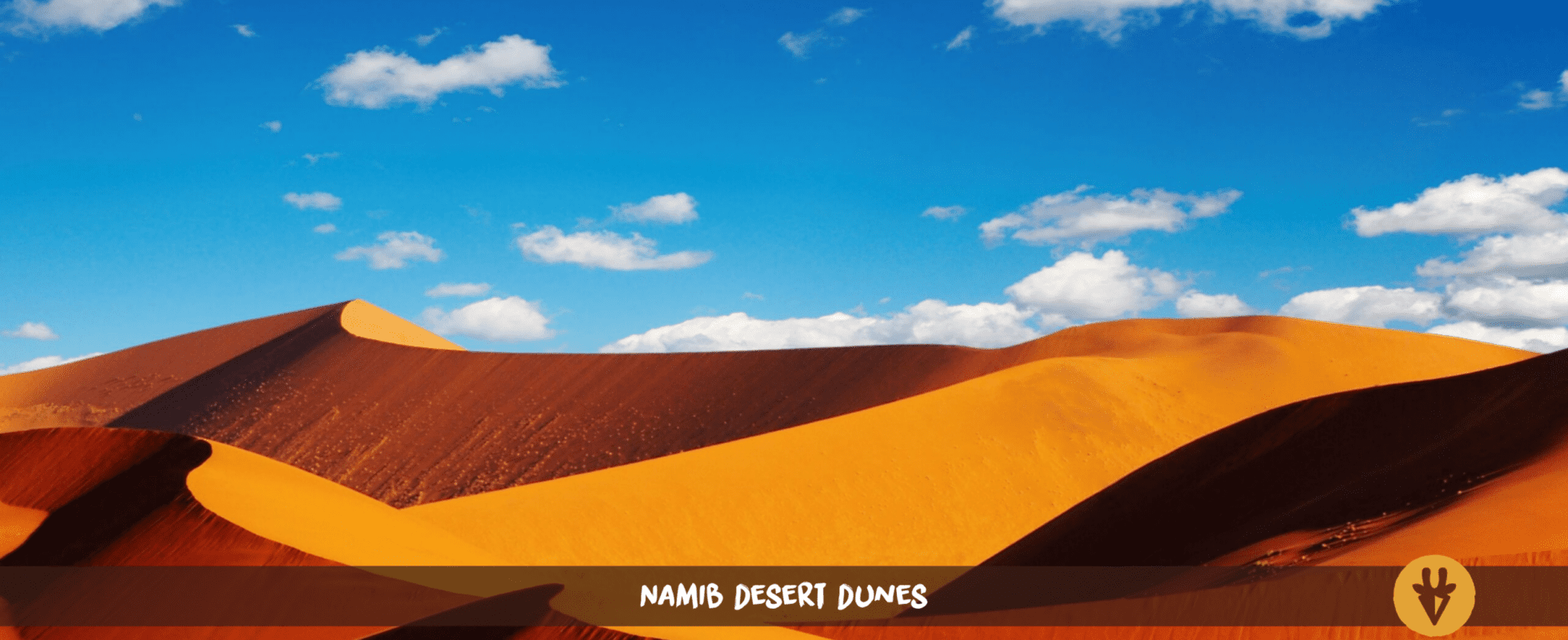 Dunes ondulantes du désert du Namib sous un ciel bleu parsemé de nuages blancs.