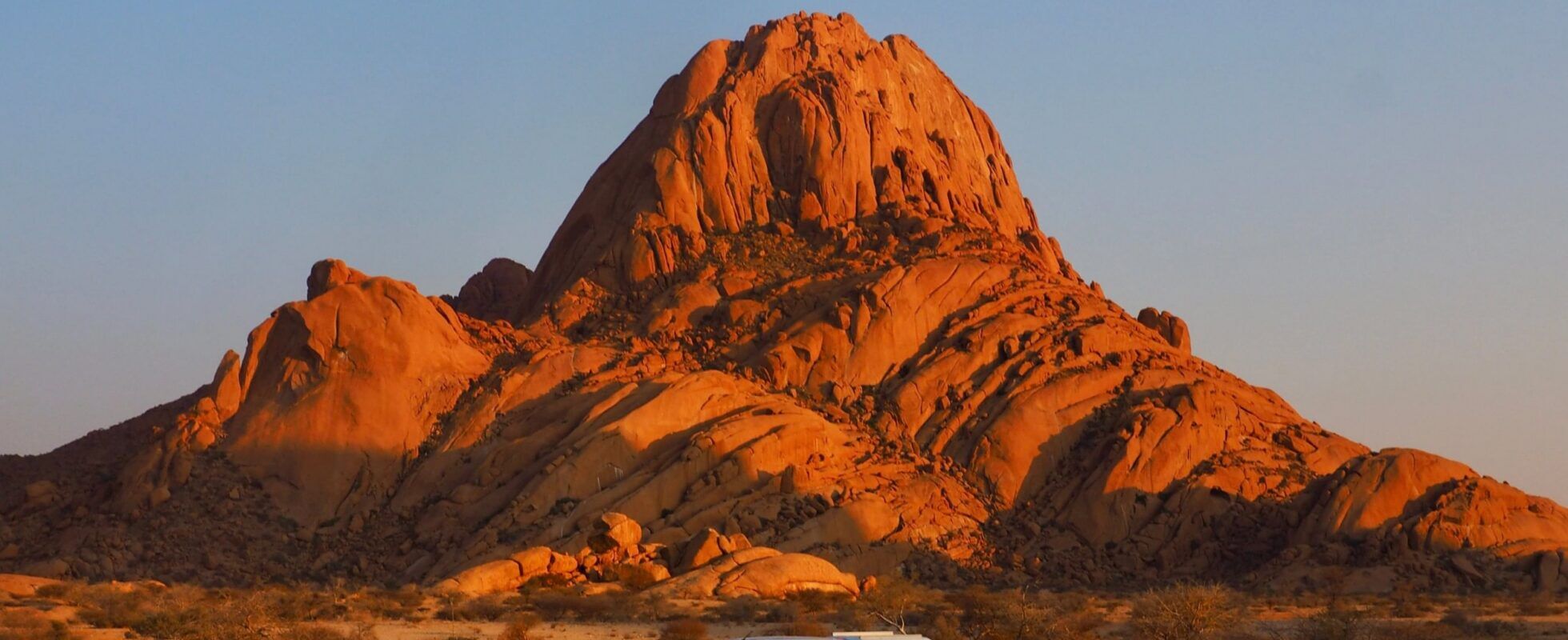 Safari vehicle parked below Spitzkoppe in sunset